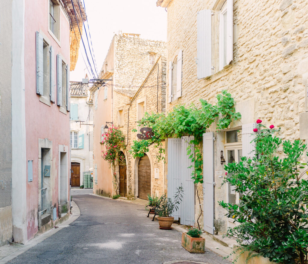 Pretty street in Provence with pastel buildings and doors covered with flowers.
